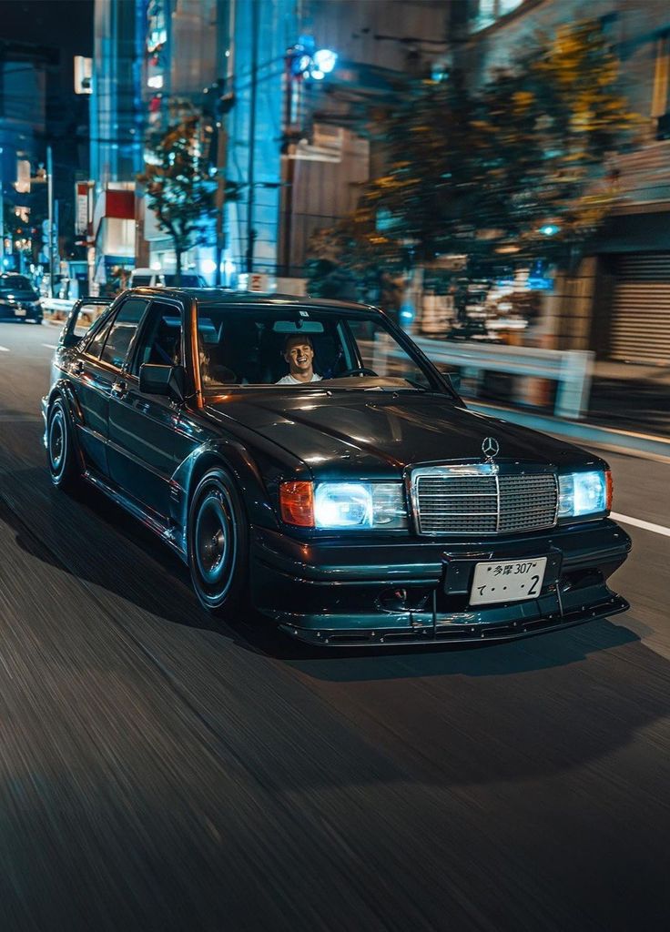 a black car driving down a city street at night