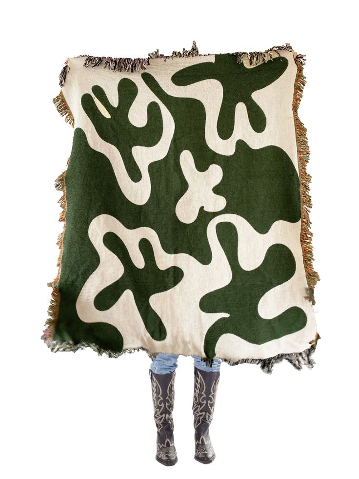 a woman is holding up a green and white blanket with an animal print on it