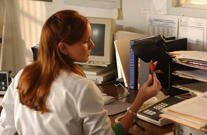 a woman sitting at a desk holding a piece of paper