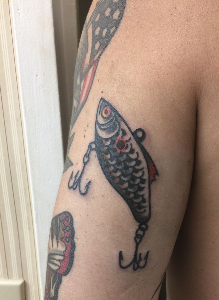 a man with a fish tattoo on his arm holding a fishing hook and an american flag