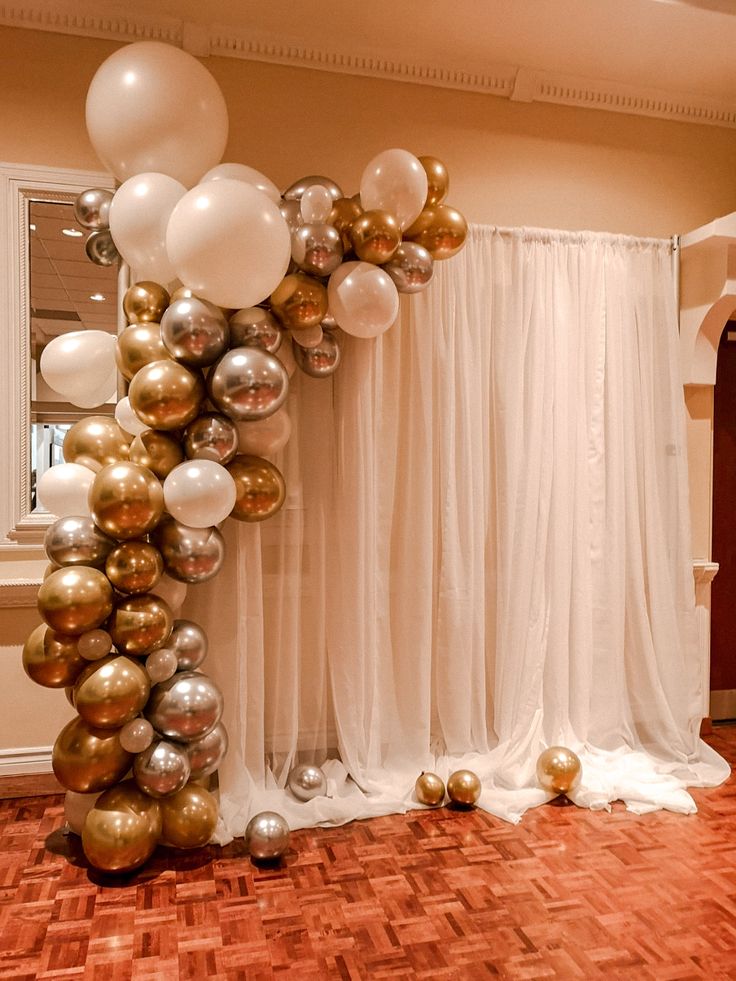 the balloon arch is decorated with gold, silver and white balloons