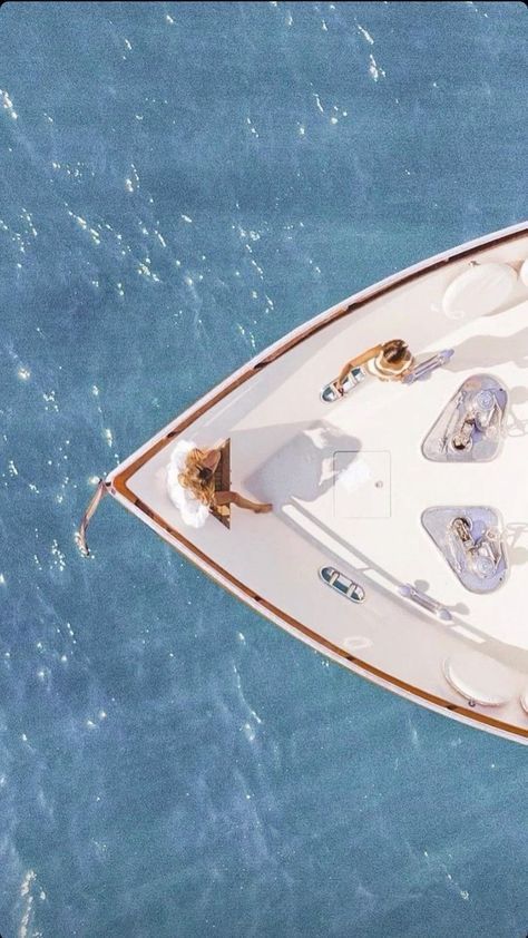 an aerial view of a white boat in the ocean with two people on it's deck