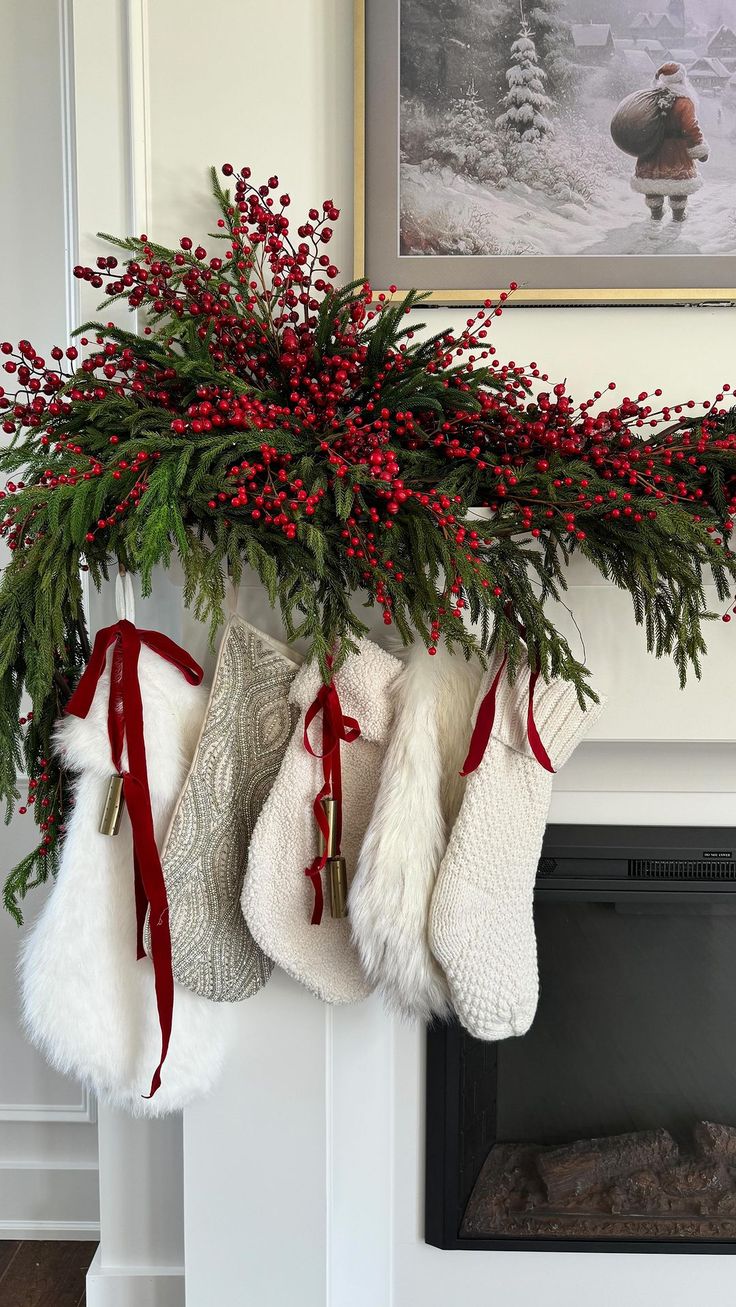 stockings hanging from a mantel decorated with red berries and greenery