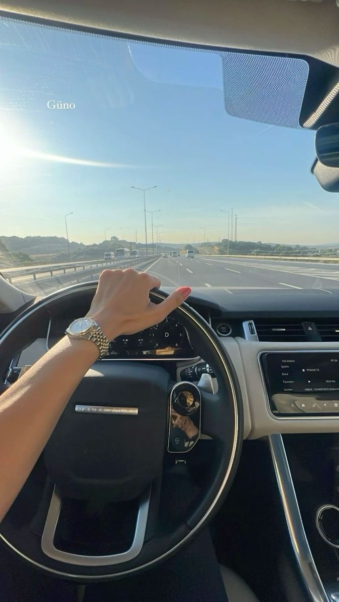 a woman is driving her car on the highway and she has her hand on the steering wheel