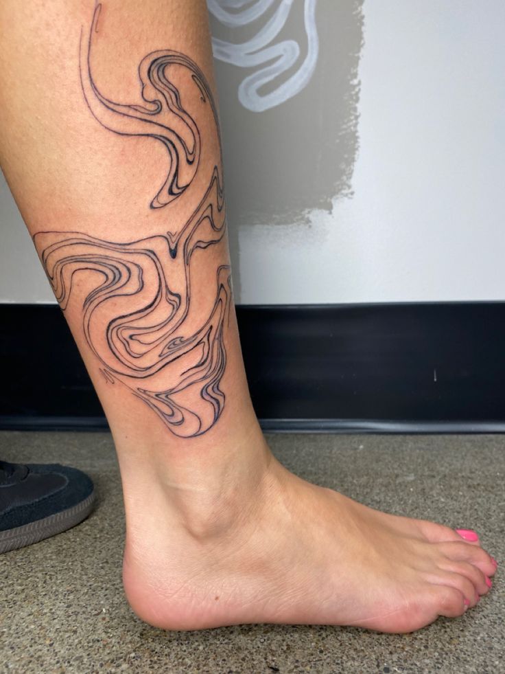 a woman's foot with a tattoo design on the side of her leg,