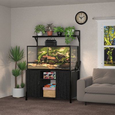 a living room filled with furniture and a fish tank on top of a stand in front of a window