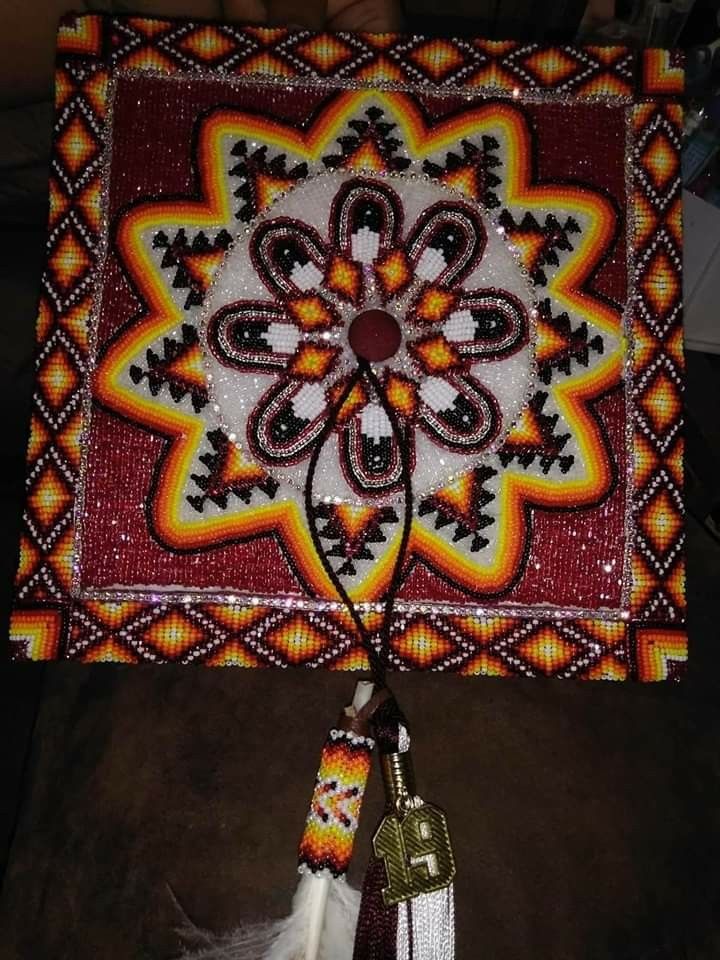 a decorative wall hanging made with beads and beadwork on a brown couch next to a white feather