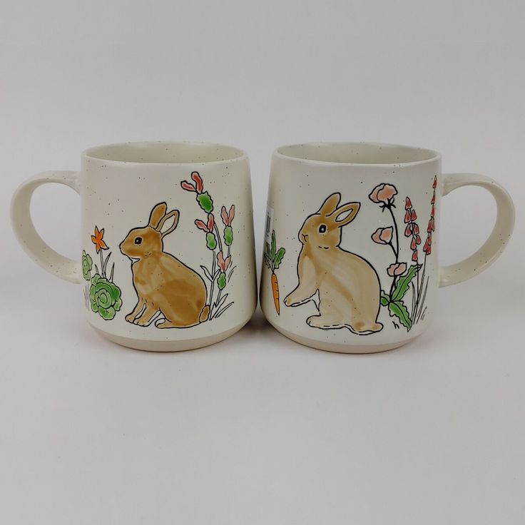 two coffee mugs with rabbits painted on them