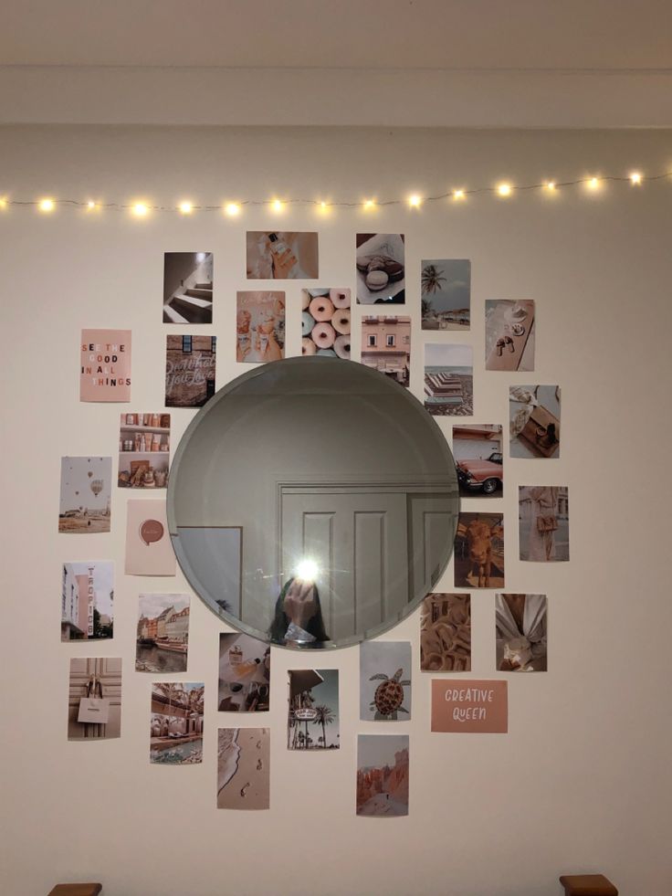 there is a mirror on the wall with pictures all over it and lights strung above