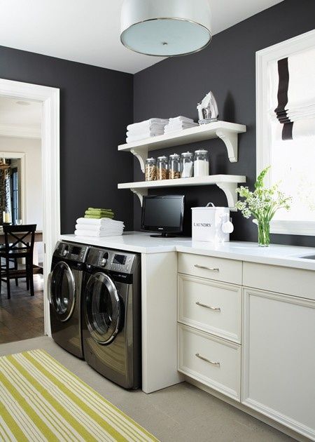 a washer and dryer in a room with white cabinets, black walls and yellow striped rug