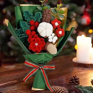 a bouquet of red and white flowers sitting on top of a table next to a lit candle