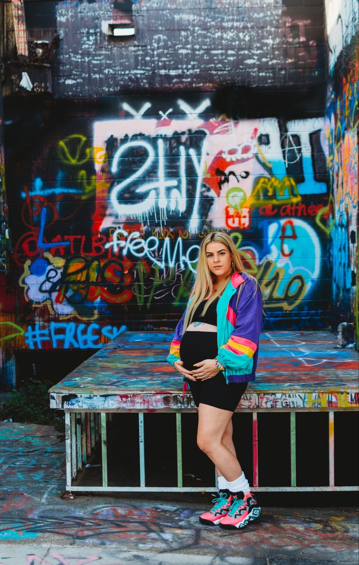 a woman standing in front of graffiti covered wall