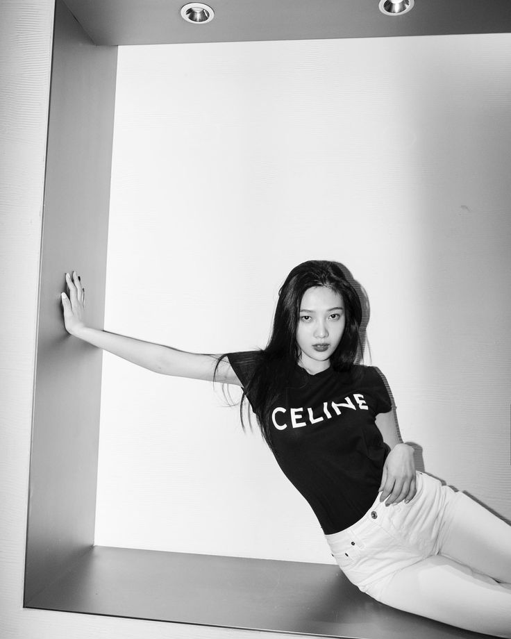 black and white photograph of a woman leaning against a wall with her arms outstretched in the air