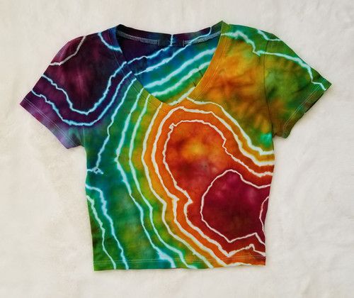 a colorful tie - dyed t - shirt is laying on a white surface and it looks like an abstract painting