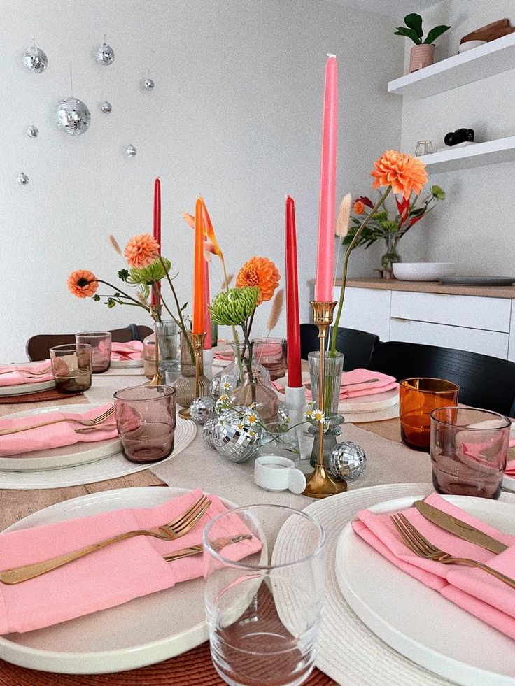 the table is set with pink napkins and silverware