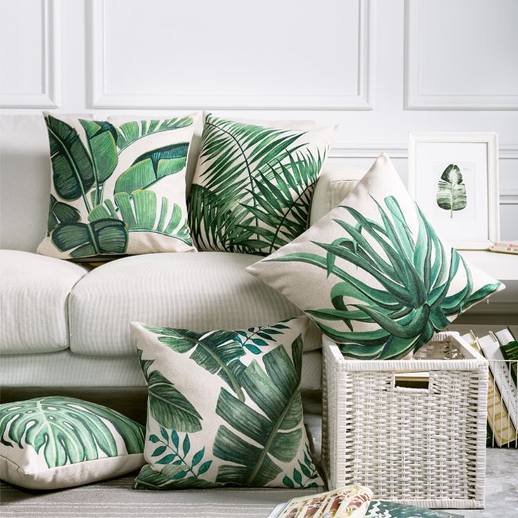 a living room filled with white furniture and green pillows on top of each other's cushions