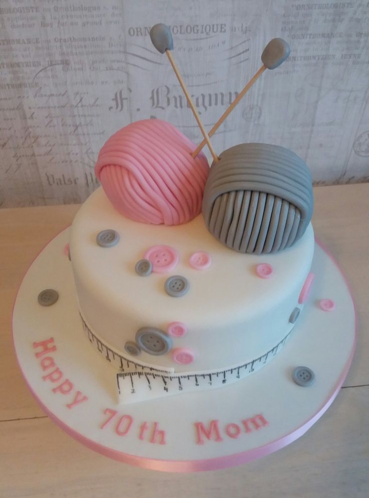 a birthday cake decorated with two balls of yarn and knitting needles on top of it