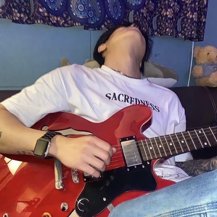 a person laying down with a red guitar