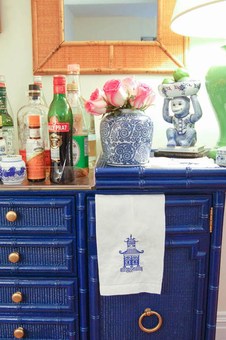 a blue dresser with various bottles and vases on it's top, along with a tea towel hanging from the drawer