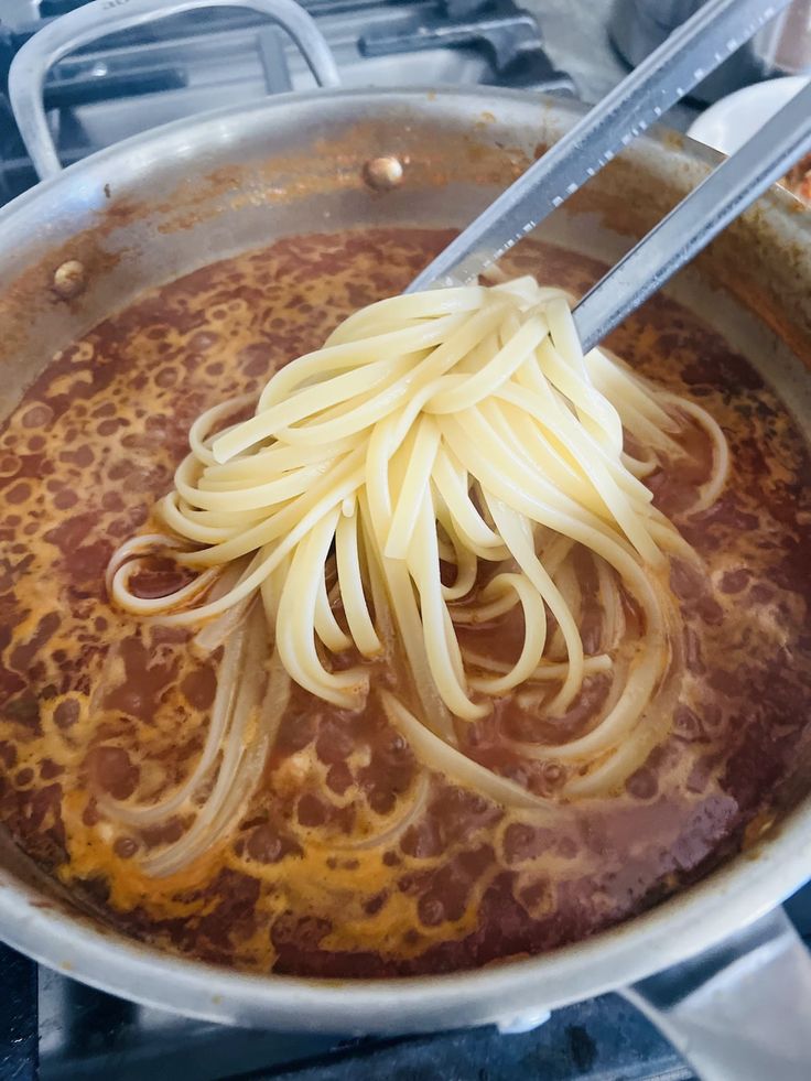 a pot filled with pasta and sauce on top of a stove