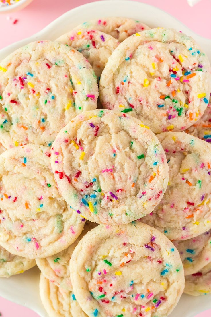 sprinkled cookies in a white bowl on a pink surface with confetti