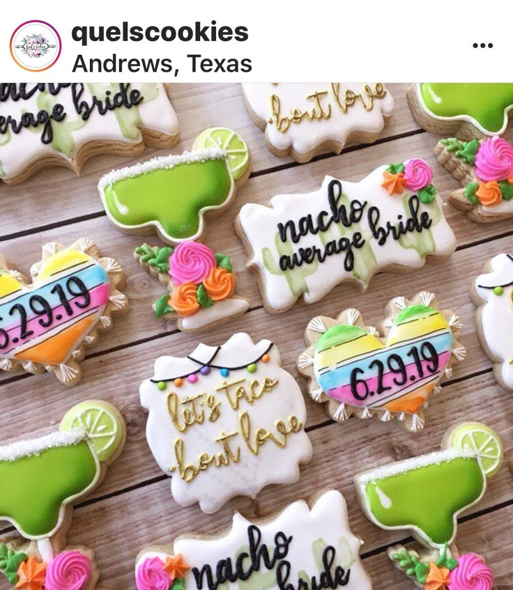 some decorated cookies are sitting on a wooden table with the names of their wedding guests