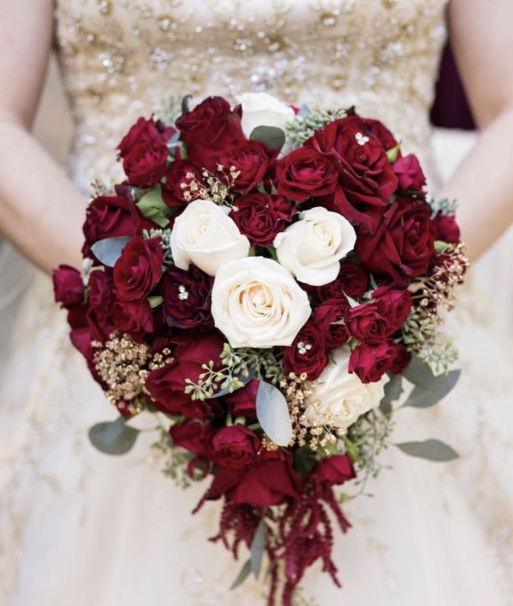 a bride holding a bouquet of red and white roses