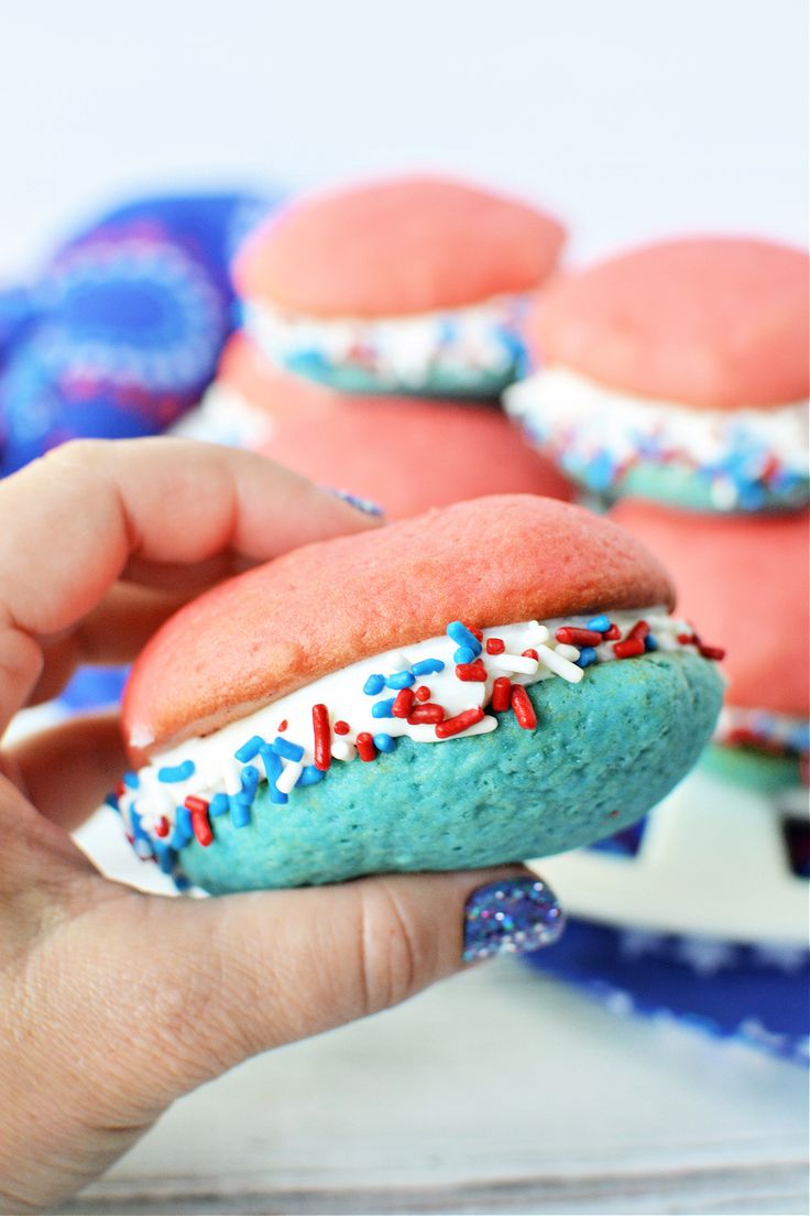 a hand holding a red, white and blue frosted doughnut with sprinkles