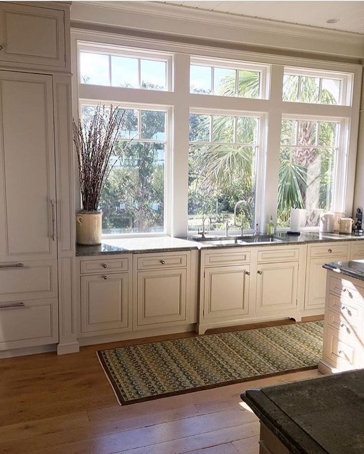 an image of a kitchen setting with white cabinets and wood flooring in the middle