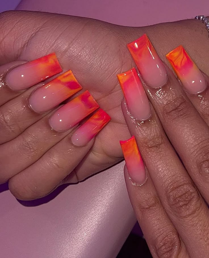 two hands with orange and pink nail designs on them