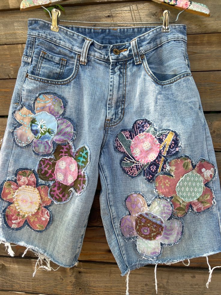 a pair of jean shorts with flower appliques on them