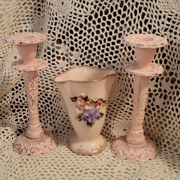 three pink vases sitting next to each other on a lace covered tablecloth,