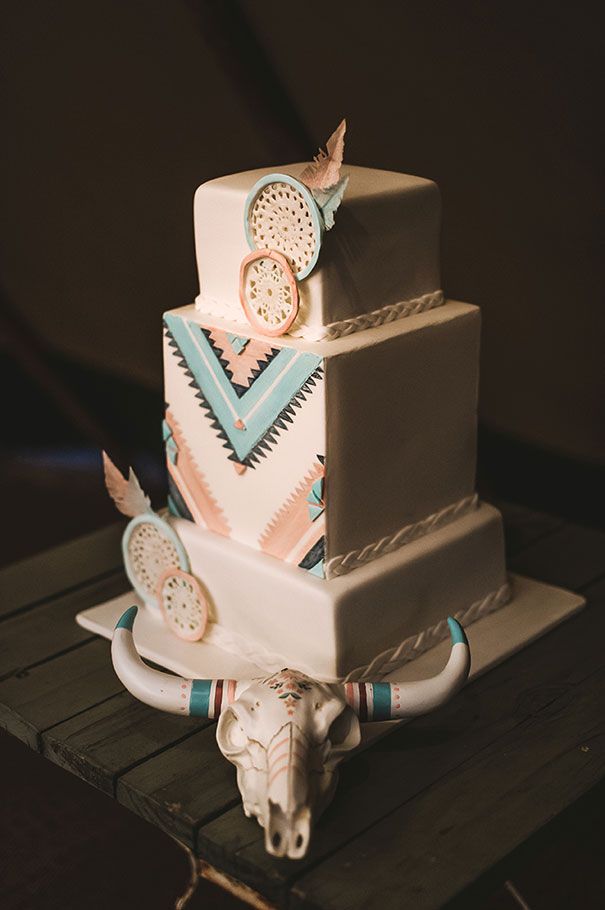 a multi layer cake sitting on top of a wooden table next to a cow skull