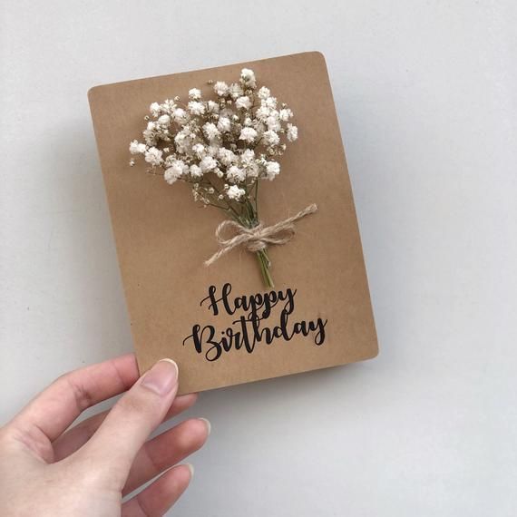 a hand holding a birthday card with baby's breath