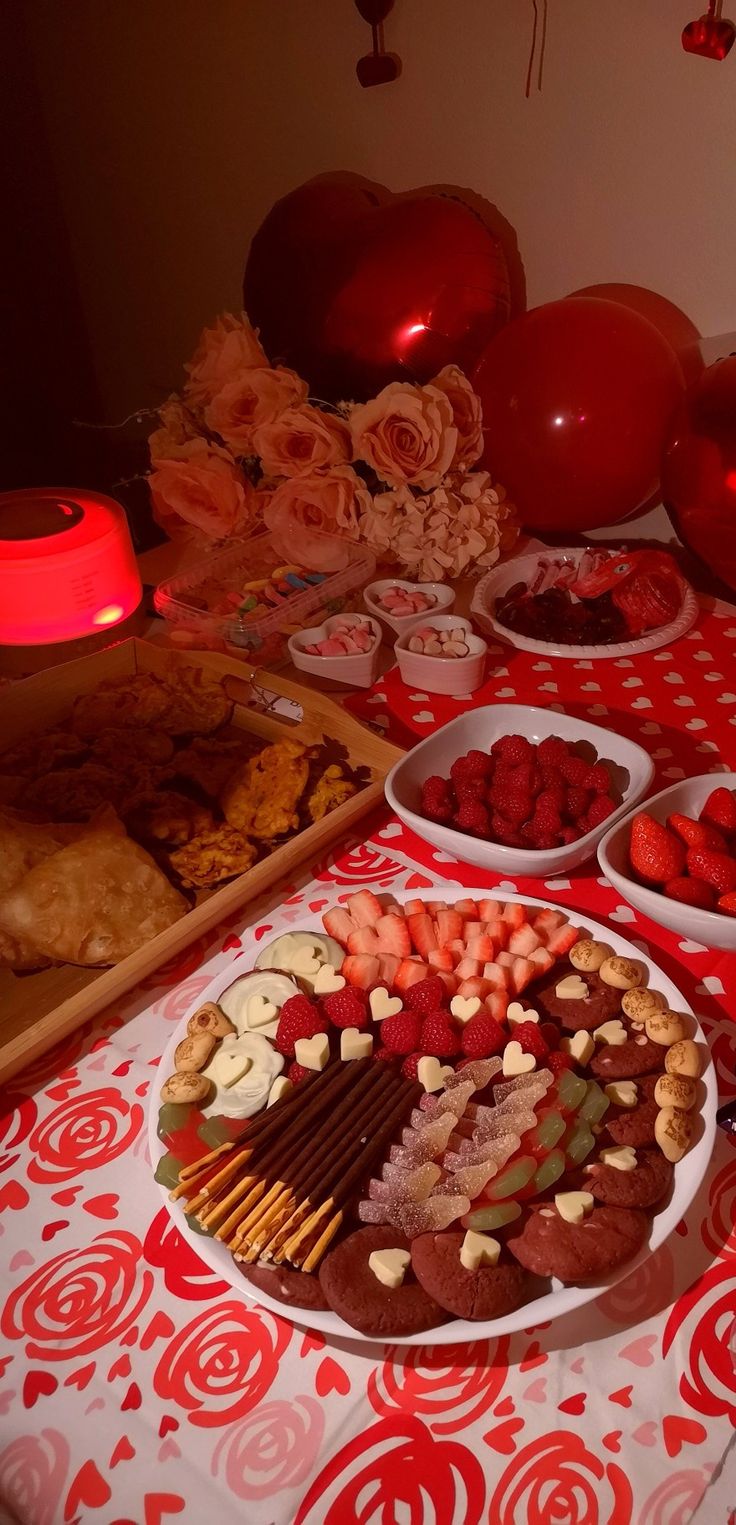 a table topped with lots of desserts and plates filled with food next to balloons