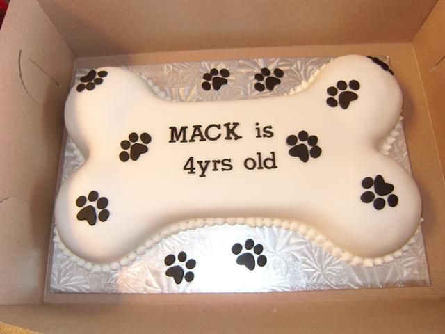 a birthday cake in the shape of a dog bone with paw prints on it and words that read mack is 4yrs old