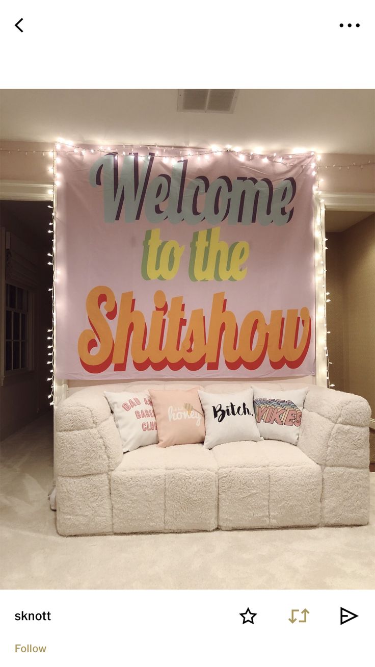 a welcome to the shitshow sign in front of a couch with pillows on it