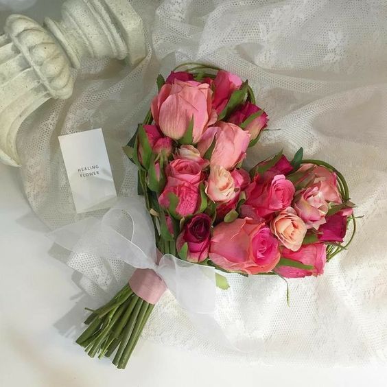 a bouquet of pink roses sitting on top of a white table cloth next to a card