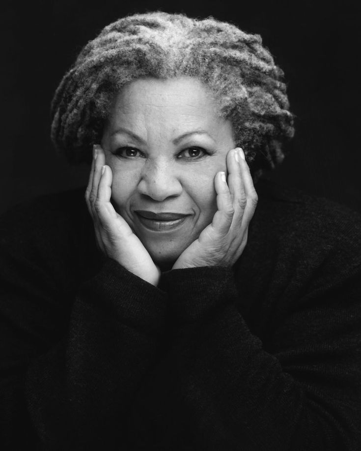 a black and white photo of a smiling woman with her hands on her chins