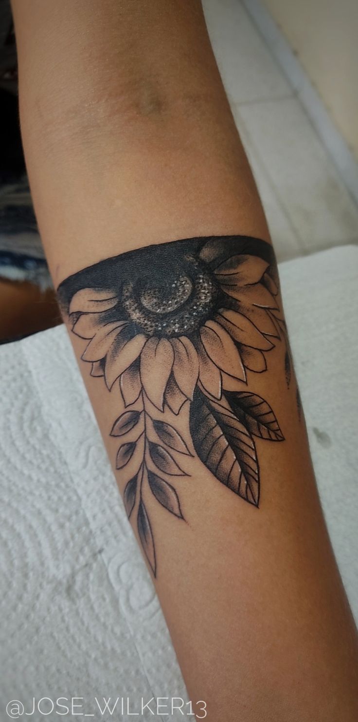 a woman's arm with a sunflower tattoo on it