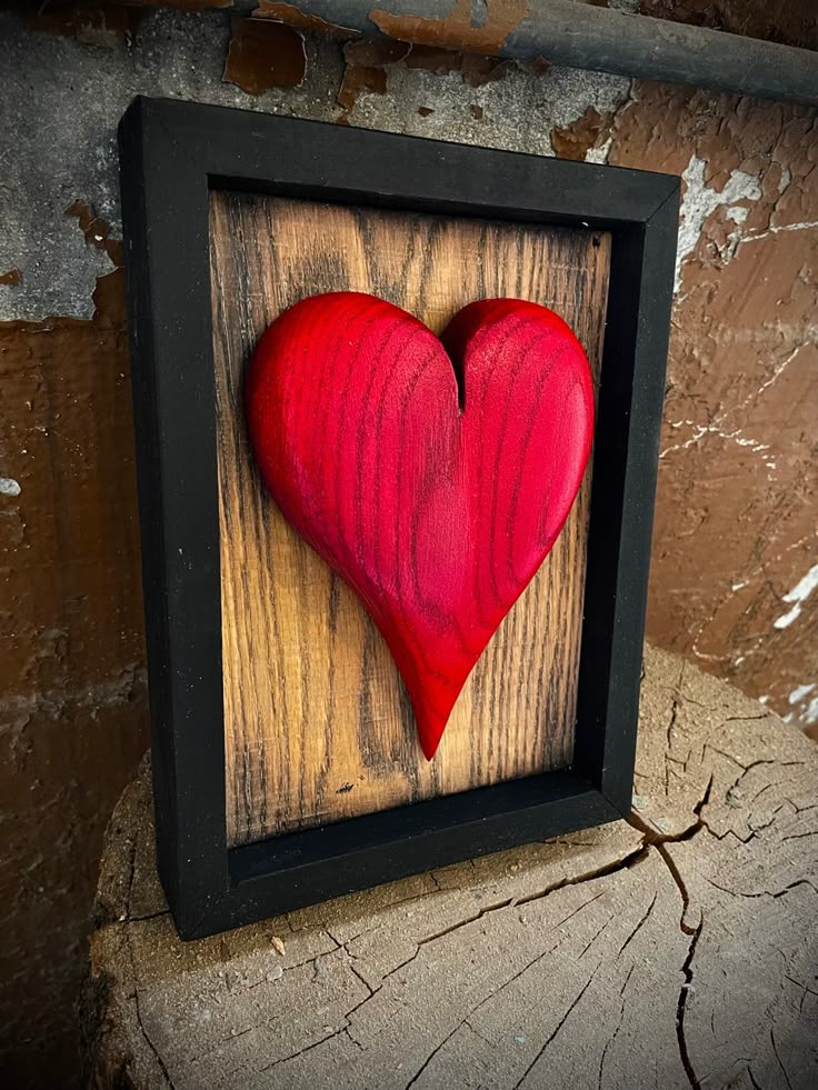 a red heart in a black frame on a wooden surface