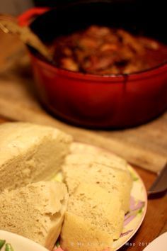 two pieces of bread sitting on top of a plate next to a bowl of food