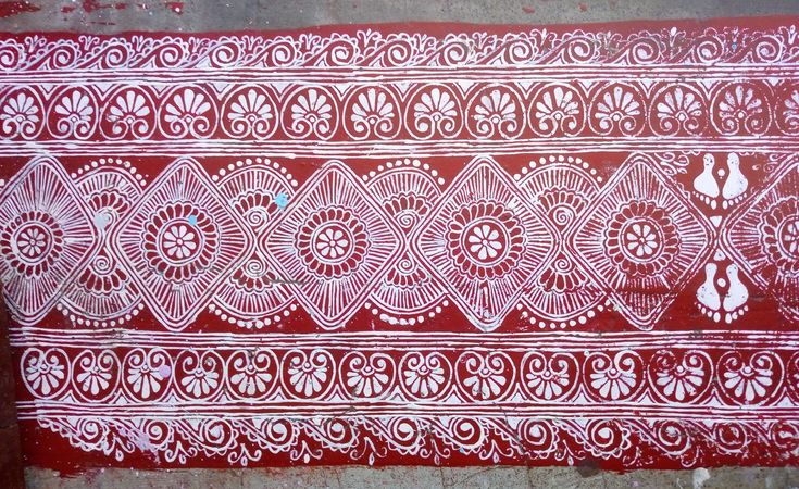 a red and white painting on the side of a building with designs painted on it