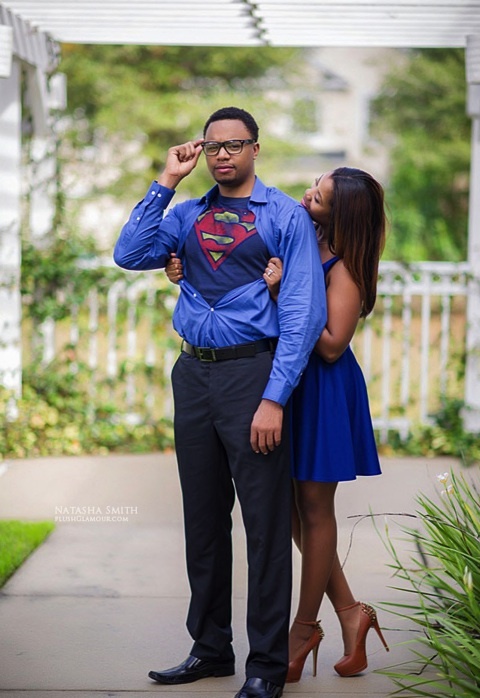 a man in a superman shirt is standing next to a woman wearing a blue dress