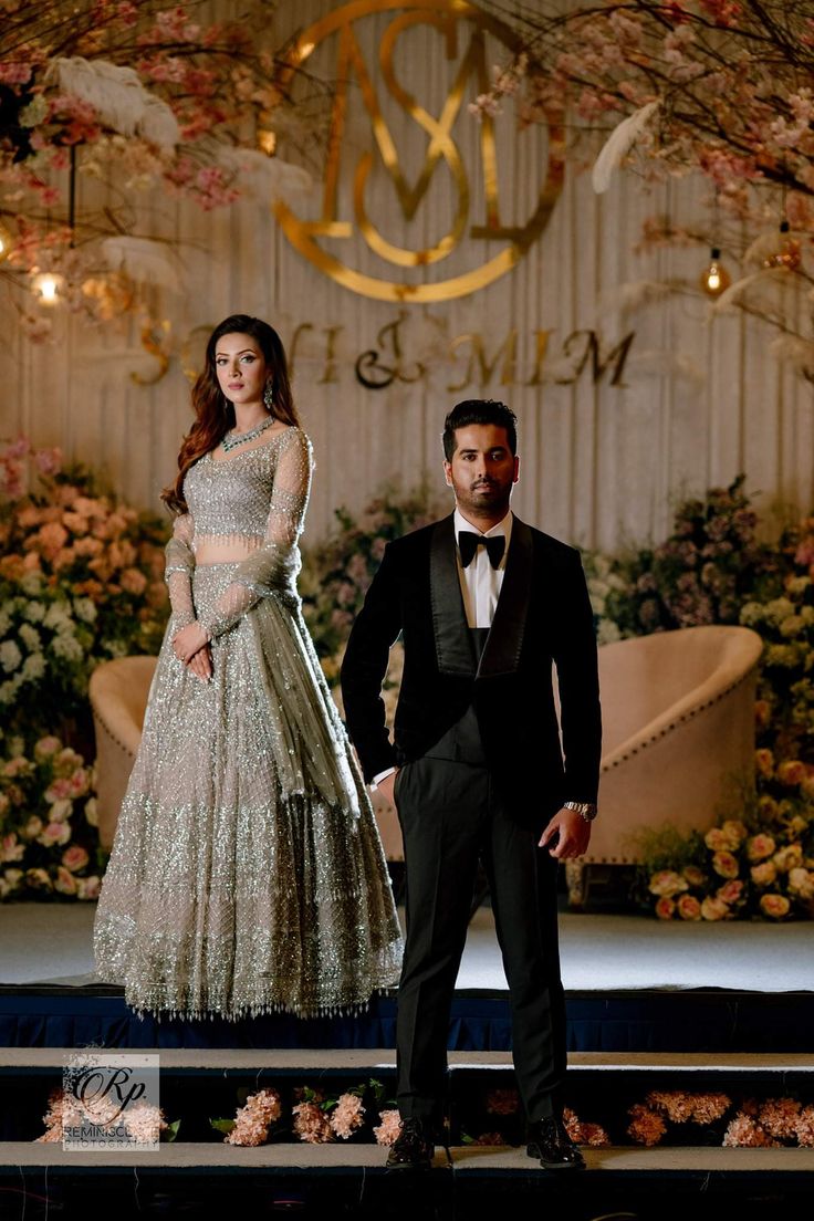 a man standing next to a woman in a dress on a stage at a fashion show