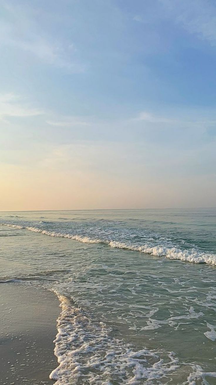 two people walking on the beach with surfboards