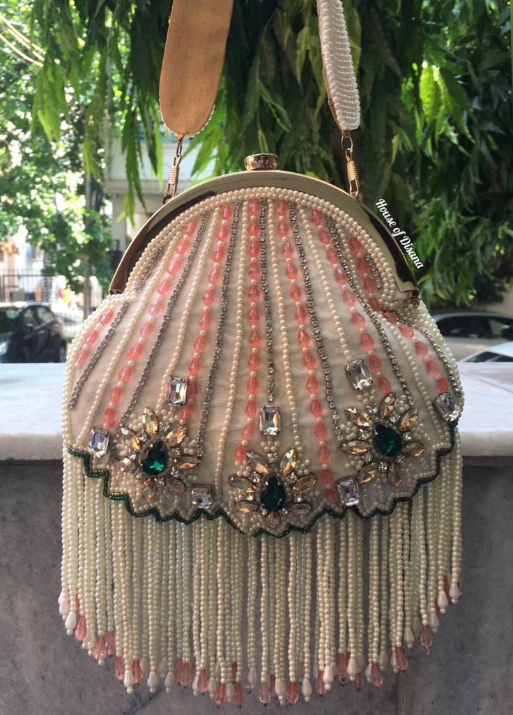 This is a beautiful handcrafted potli bag made with love.It has intricate handwork which showcases the Indian craftsmanship by our local artisans. It comes with a matching pearl handle. Details  - Both side handwork  - Fabric lining on the inside to keep your belongings safe  - Metal lock closure  - Golden metal knob - Detachable handle This clutch can be worn as a crossbody bag or a shoulder bag with the sling chain or can simply be carried in hand.It is spacious enough to carry mobile phones, Wedding Gifts Indian, Ivory Clutch, Crochet Free Patterns, Handmade Fabric Bags, Bags Patterns, Indian Accessories, Potli Bag, Indian Gifts, Embellished Bags