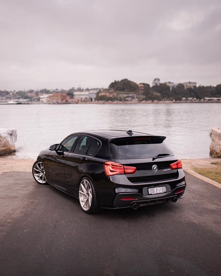 a black car parked on the side of a road next to water