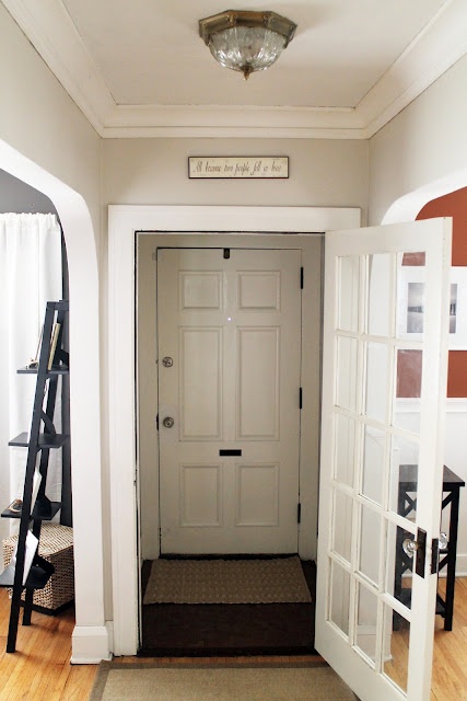 an entry way with a white door and wooden floors