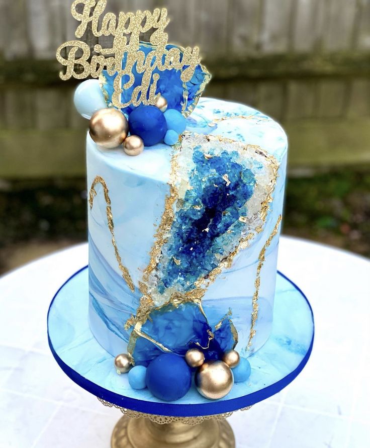 a blue and gold birthday cake sitting on top of a table